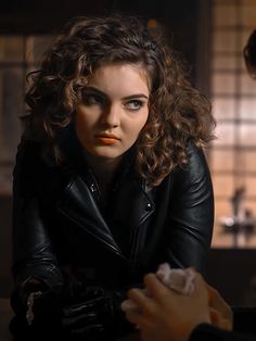 a woman in black leather jacket sitting next to a man with red lipstick on his lips