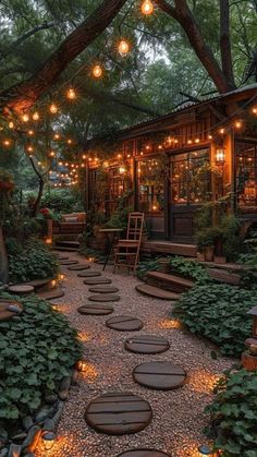 an outdoor patio with lights strung from the trees and stepping stones leading up to it