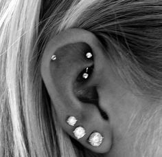 a woman's ear with three different piercings on it