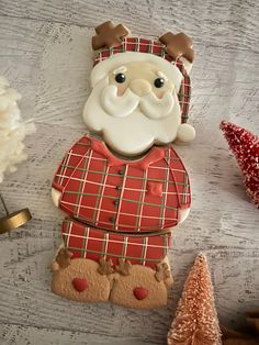 a cookie shaped like a santa clause on top of a table next to christmas trees