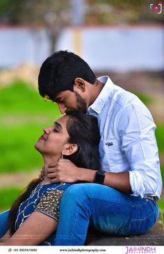 a man and woman sitting on top of each other in front of a green field