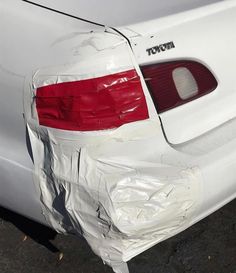 the back end of a white car that has been wrapped in plastic