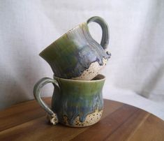 two ceramic cups sitting on top of a wooden table