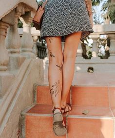 a woman walking up some steps with her foot in the air and tattoos on her leg