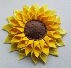 a sunflower made out of felt sitting on top of a white table next to a wall