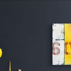 a yellow vase sitting next to a black wall