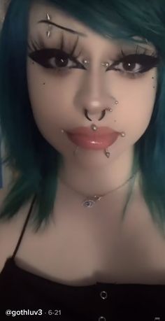 a woman with green hair and piercings on her face