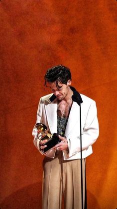 a man standing in front of a microphone and holding an award for best male performance