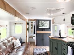 a living room and kitchen area in a mobile home with wood floors, white walls and green cabinets