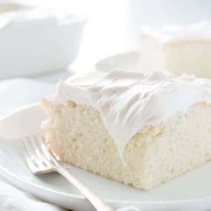 a piece of cake on a white plate with a fork and bowl in the background