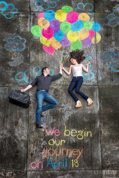 a man and woman laying on the ground next to a wall with balloons drawn on it