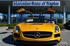 a yellow sports car parked in front of a mercedes benz dealership