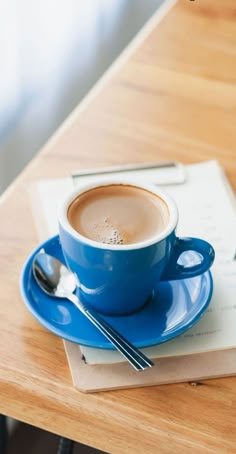 a cup of coffee sitting on top of a blue saucer next to a piece of paper