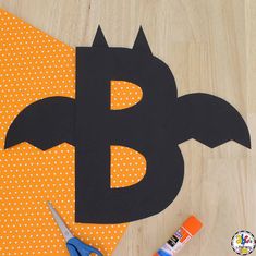 paper cut out of the shape of a bat with scissors and glue next to it