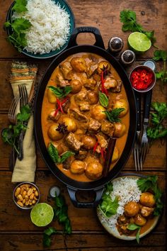 chicken curry with rice and garnishes in a pan on a wooden table