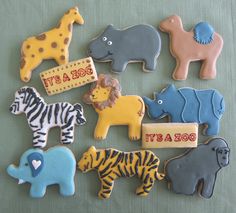 decorated cookies are arranged in the shape of animals and zebras on a green tablecloth