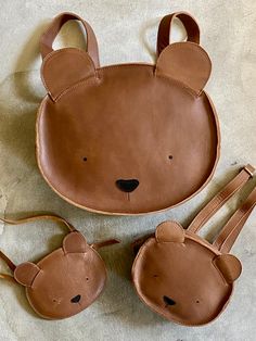 three pieces of brown leather with bear ears on the top and bottom, one is shaped like a bag