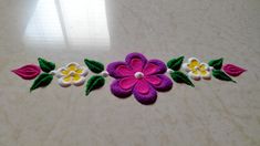 a close up of a flower on a table with other flowers in the background and a window behind it