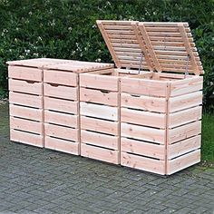 several wooden crates sitting next to each other on a brick sidewalk in front of bushes