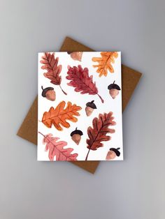 a card with watercolor leaves and acorns on it