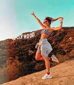 a woman standing on top of a dirt hill next to a sign that says hollywood