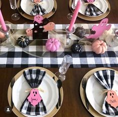 the table is set with black and white checkered cloths, pink napkins, and pumpkin decorations