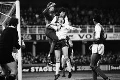 two soccer players jump for the ball in front of an opposing team during a game