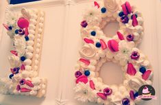 two cakes decorated with flowers are displayed on the wall next to each other in the shape of the number eight