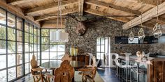 an open kitchen and dining area with stone walls, wood ceilinging and large windows