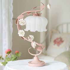 a white cake with flowers on it sitting on top of a round table next to a window