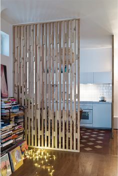 a room divider made out of wooden slats with string lights on the floor