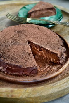 a chocolate cake with one slice cut out on a plate next to a knife and fork