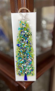 a glass ornament hanging from a wooden post with a blue ribbon on it