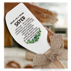 a wooden spatula with the words sister on it and a ribbon tied around it