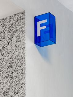 a blue f logo mounted to the side of a wall next to a white wall