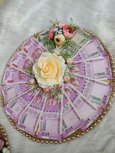 a pink and white rose sitting on top of a pile of money with gold beads