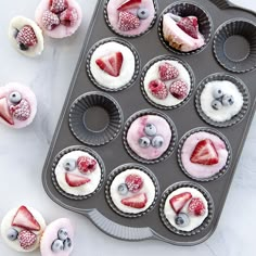 cupcakes with berries and blueberries in them on a baking tray, ready to be eaten