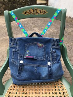 an old pair of blue jeans is sitting on a green plastic chair with colorful straps