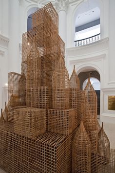 a sculpture made out of bamboo sticks in a large room with white walls and windows