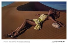 a woman laying on top of a sand dune