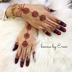 two hands with henna designs on them, one is red and the other is white