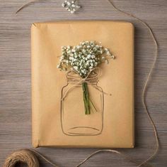 a bouquet of baby's breath in a mason jar tied to a brown paper bag