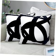 two black and white pillows sitting on top of a couch next to a potted plant