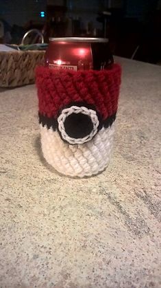 a red and white knitted coffee cup cozying on top of a kitchen counter