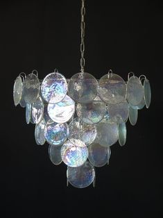 a chandelier hanging from a chain on a black background with lots of glass discs