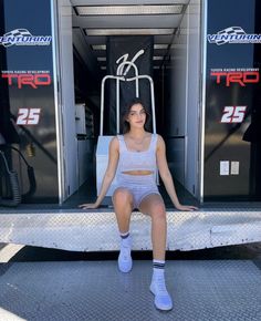 a woman sitting on the back of a truck with her legs crossed and wearing white socks