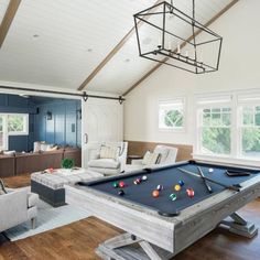 a pool table in the middle of a living room with two couches and chairs