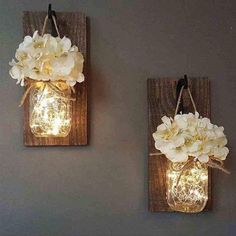 two mason jar wall sconces with flowers on them are hanging from the wall