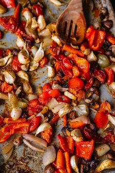 a pan filled with lots of different types of food on top of a wooden spoon