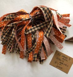 an orange and white polka dot ribbon on a piece of paper next to a tag